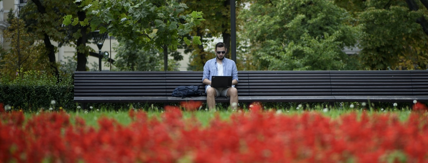 Blagoslav Mihaylov sitting on a bench and typing on a laptop